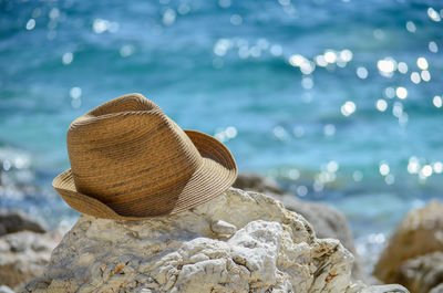 Close-up of sun hat on rock by sea