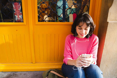 Young woman using mobile phone while sitting outdoors