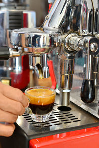 Close-up of hand holding cup at espresso maker