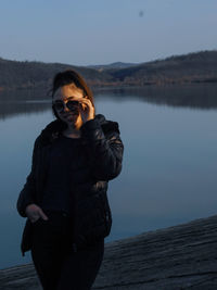 Woman standing by lake against sky