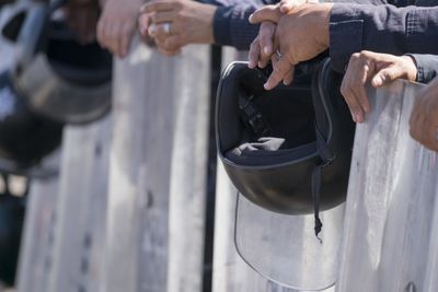 Cropped image of people on fence outdoors