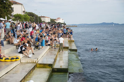 People enjoying at sea shore against sky