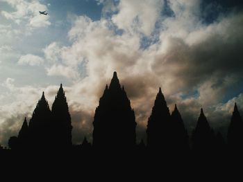 Silhouette of temple against cloudy sky