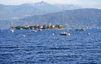 Sailboats in sea against mountains