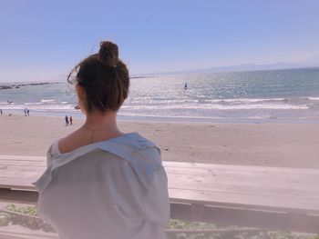 Rear view of woman standing by railing at beach