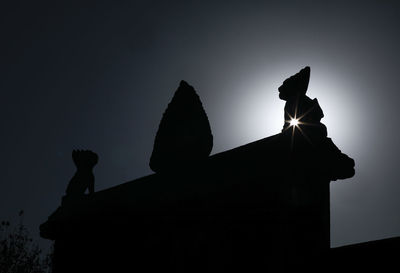 Low angle view of silhouette statue against rocks