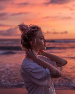 Side view of woman looking at sea during sunset