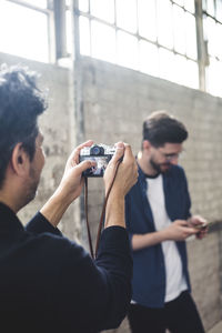 Man photographing with camera while standing on mobile phone