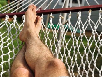 Low section of man relaxing by fence