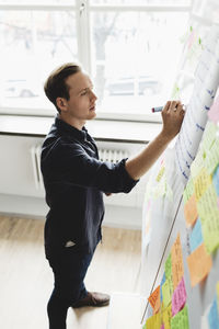 Businessman writing on whiteboard in creative office