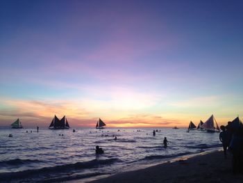 Silhouette people on beach against sky during sunset