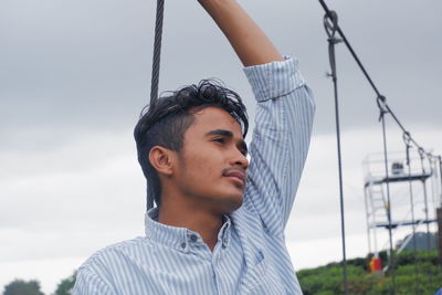 Low angle view of arabic young man standing against sky