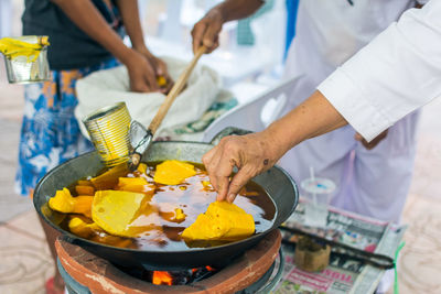 Cropped image of man analyzing wax in pan during candle festival