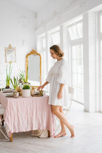 Young woman in a white dress sets a festive easter table
