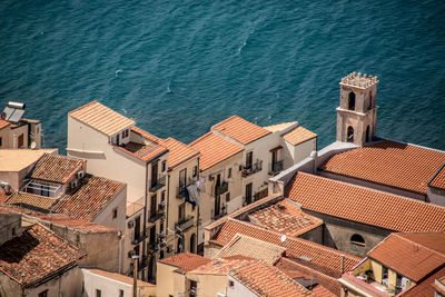 High angle view of rooftop houses against rippled water