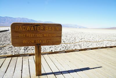 Information sign on landscape against sky - badwater basin, death valley