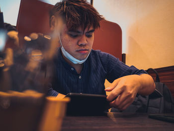 Close-up of man using digital tablet on table