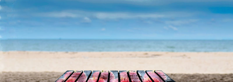 Deck chairs on beach against sky