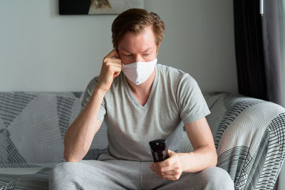 Young man using mobile phone while sitting on sofa