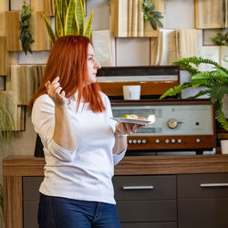 Woman eating food while standing at home