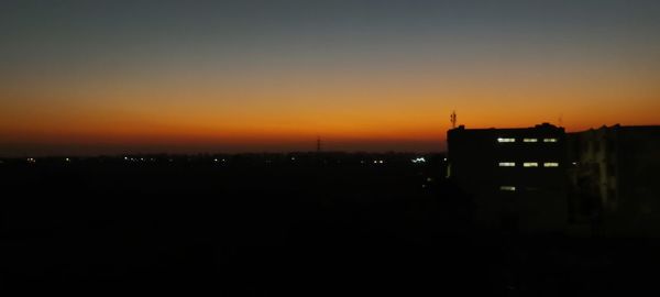 Silhouette buildings against clear sky at sunset