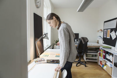 Serious woman looking at canvas while standing in creative office