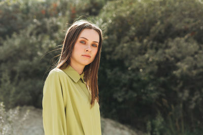 Fashion beauty portrait of young woman with long hair in green organic suit outdoors