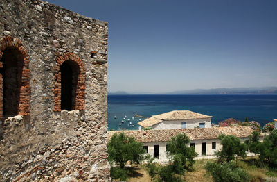 Old building by sea against clear sky