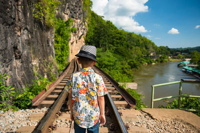 Rear view of woman walking on footbridge against mountain