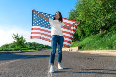 Portrait of smiling pretty young woman holding waving american flag. usa celebrate 4th of july. 