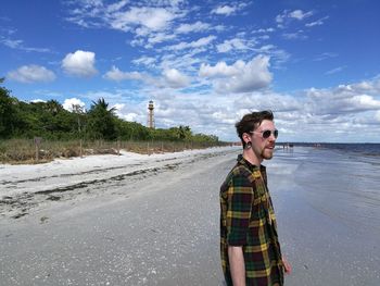 Young man standing on road against sky