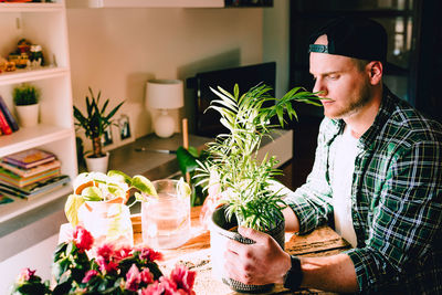 Young man sitting by potted plant on table