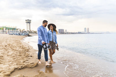 Spain, barcelona, couple walking barefoot on the beach