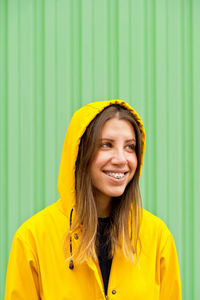 Young woman standing against green wall