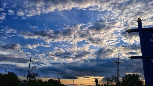 Low angle view of silhouette electricity pylon against sky