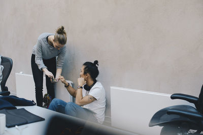 Male and female computer programmers using smart phone in office