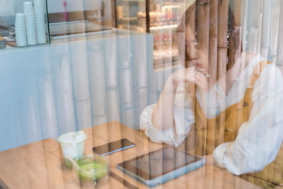 Midsection of man using mobile phone while sitting on table