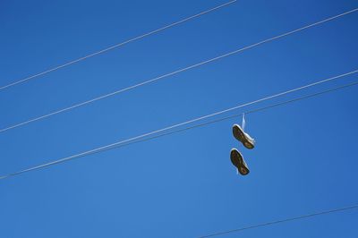 Low angle view of shoes against blue sky