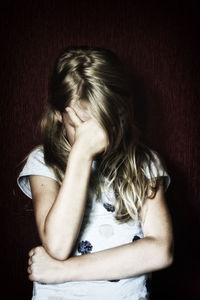 Close-up of depressed girl with head in hand by wall