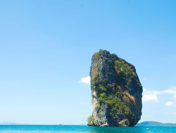 Rock formation in sea against blue sky