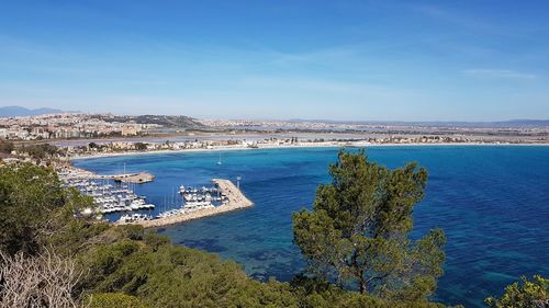 High angle view of townscape by sea against blue sky