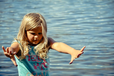 Happy girl with arms raised standing in water