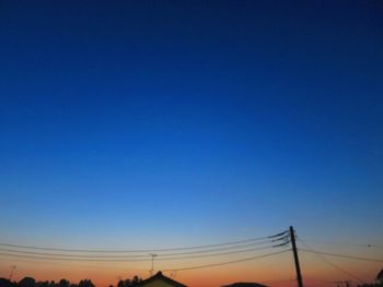 Low angle view of silhouette trees against clear blue sky