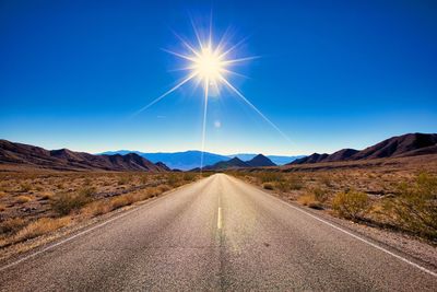 Scenic view of road amidst landscape against blue sky