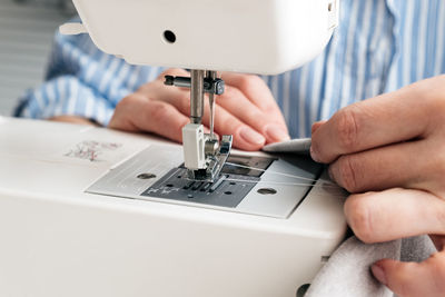 Close-up of craftswoman sewing textile on machine at workshop