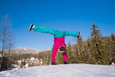 Full length of person standing on snow covered field against blue sky