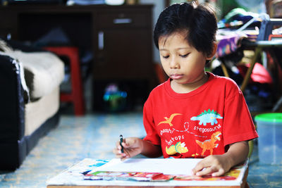 Cute boy looking at camera while sitting on table