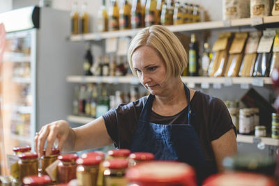 Female employee arranging jars in deli