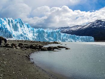 Scenic view of sea and snowcapped mountains against sky