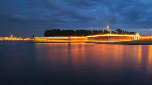 Illuminated bridge over river against sky at sunset